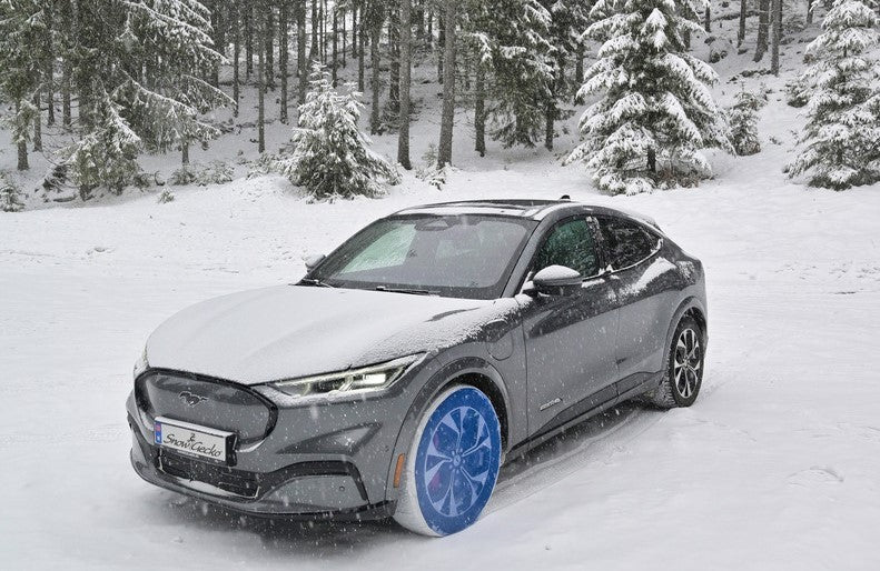 Ford Mustang mit installierten SnowGecko Schneeketten in der Winterlandschaft